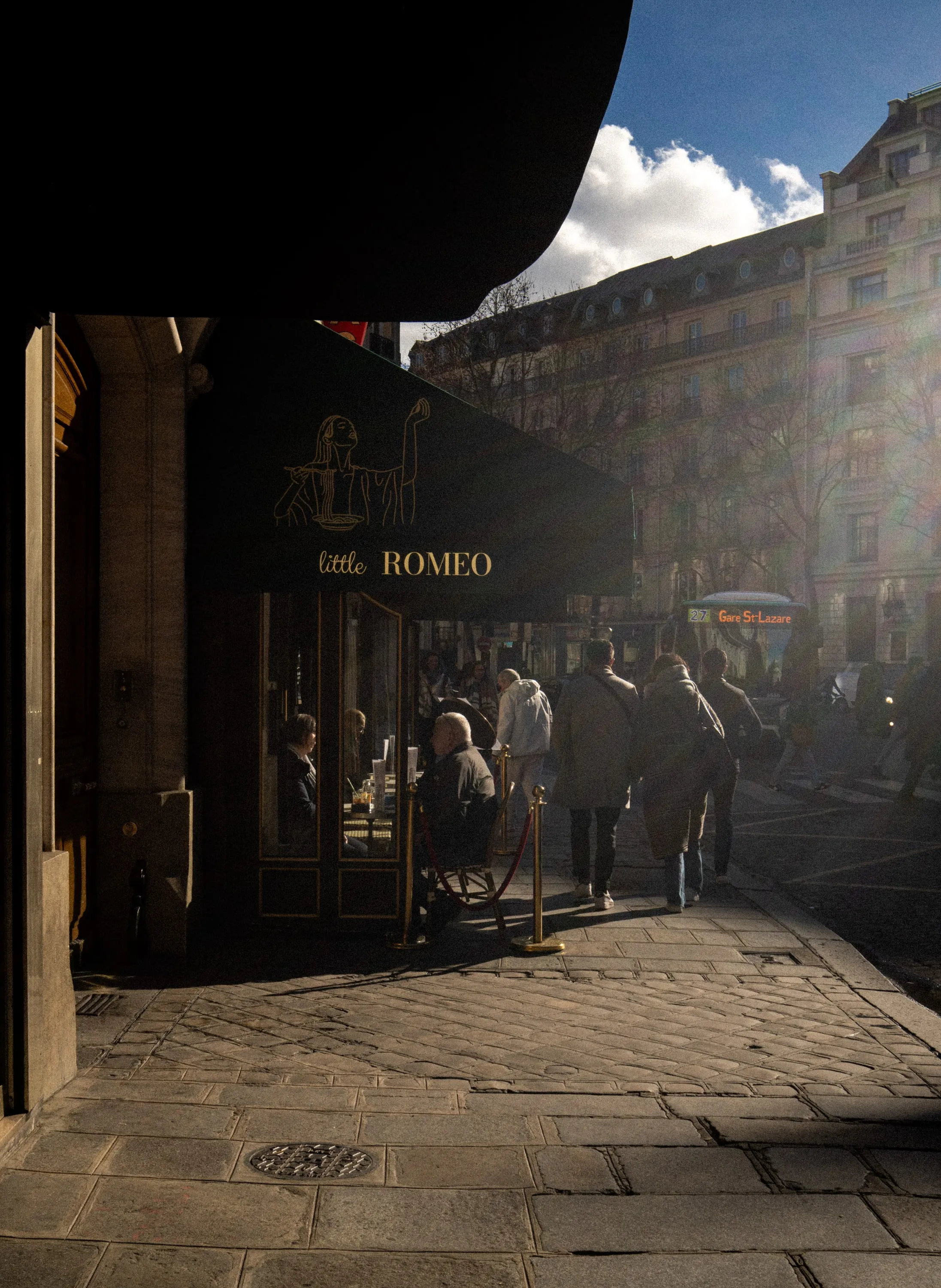 A narrow shopping arcade at dusk, shopfronts lit against the darkening sky.