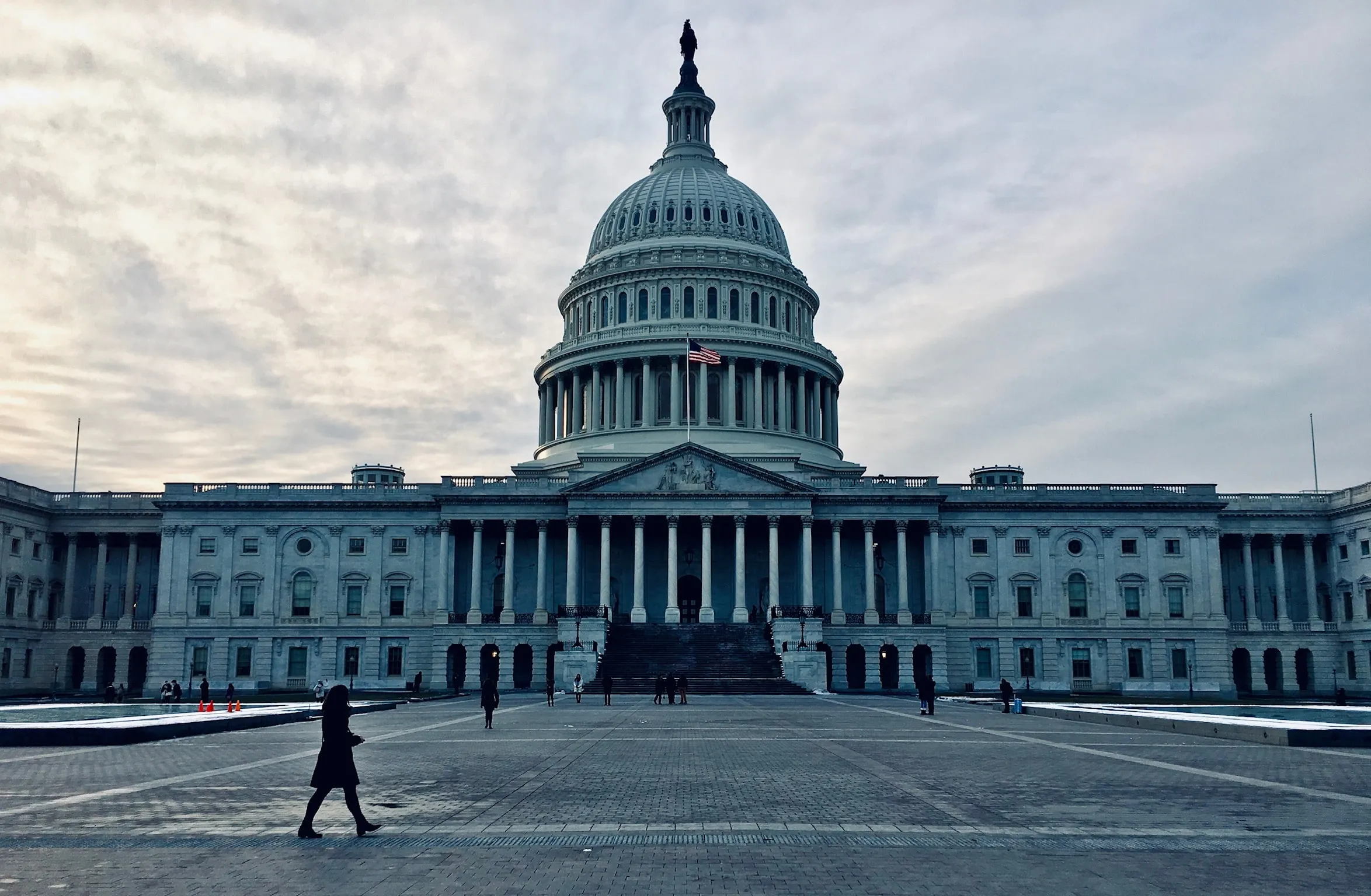 The United States Capitol with a single figure crossing the empty plaza in front of it.