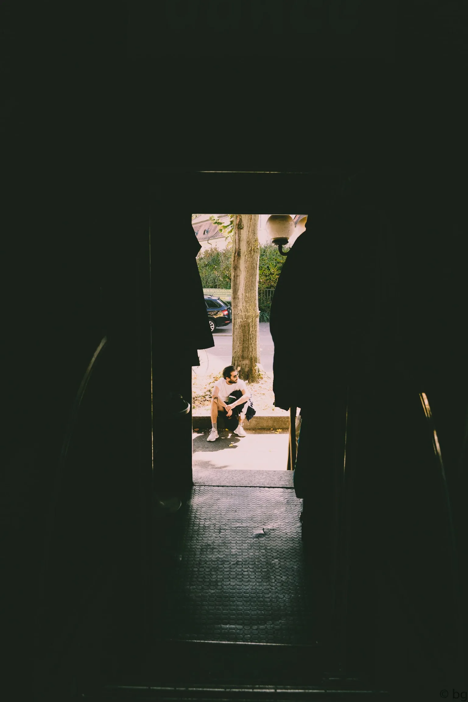 A dark doorway framing a bright street scene beyond.