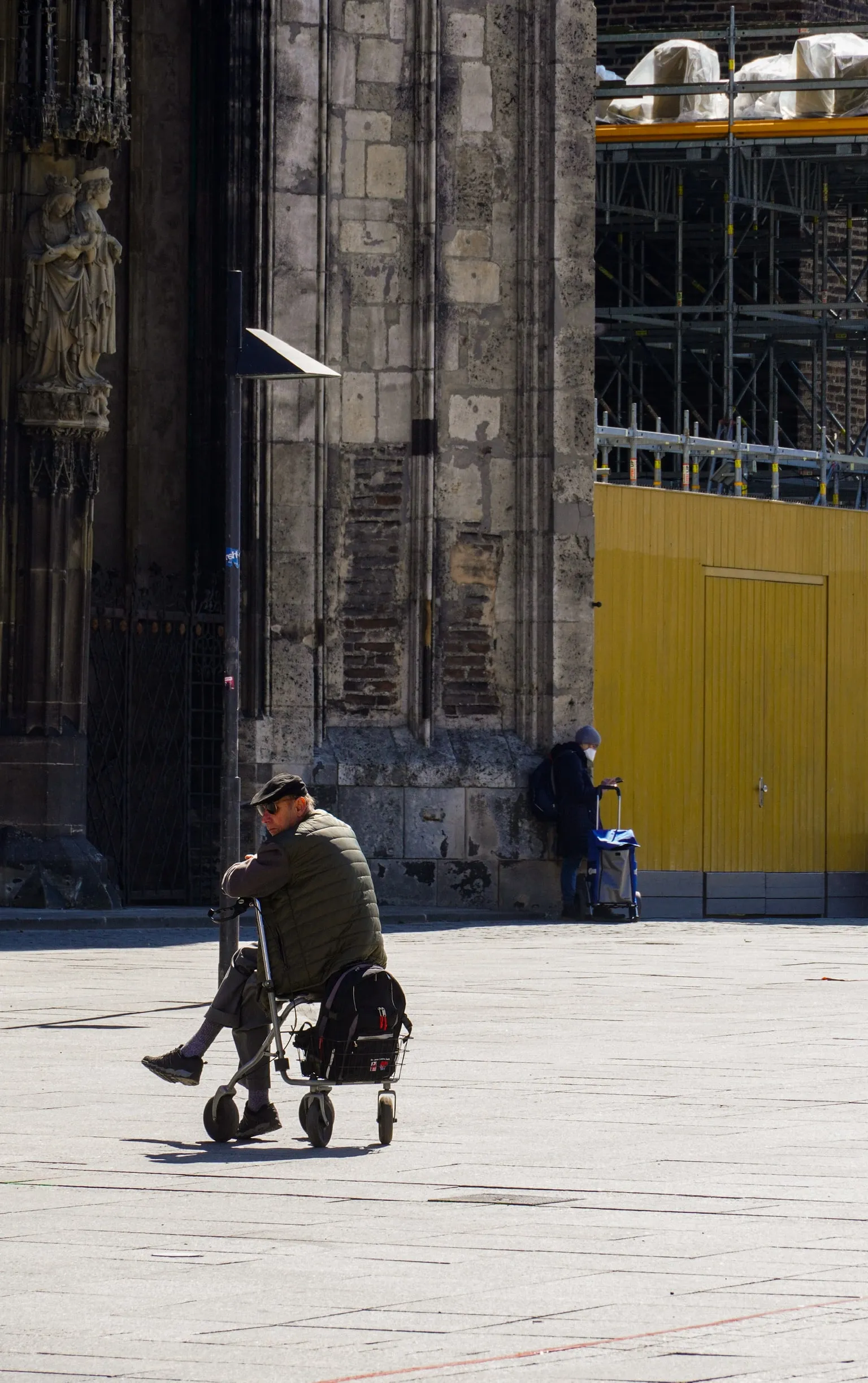 A person pushing a pram across an otherwise empty cathedral square.