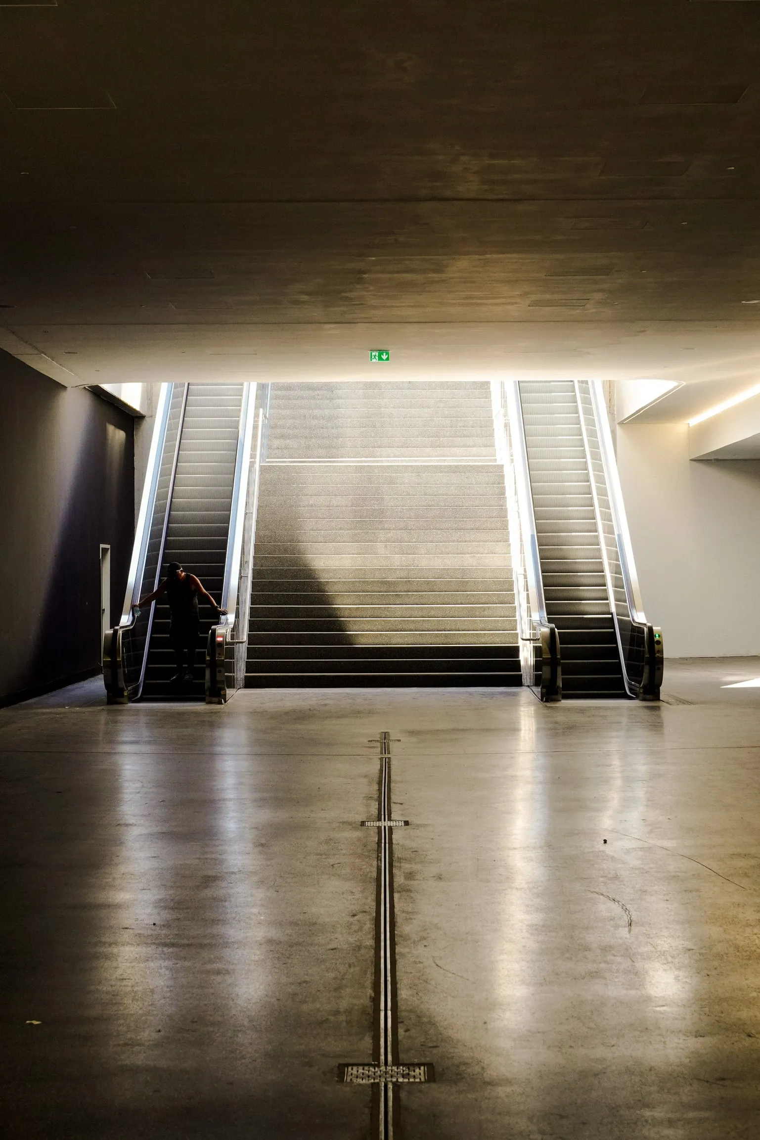 Empty escalators descending into a concrete underground station.