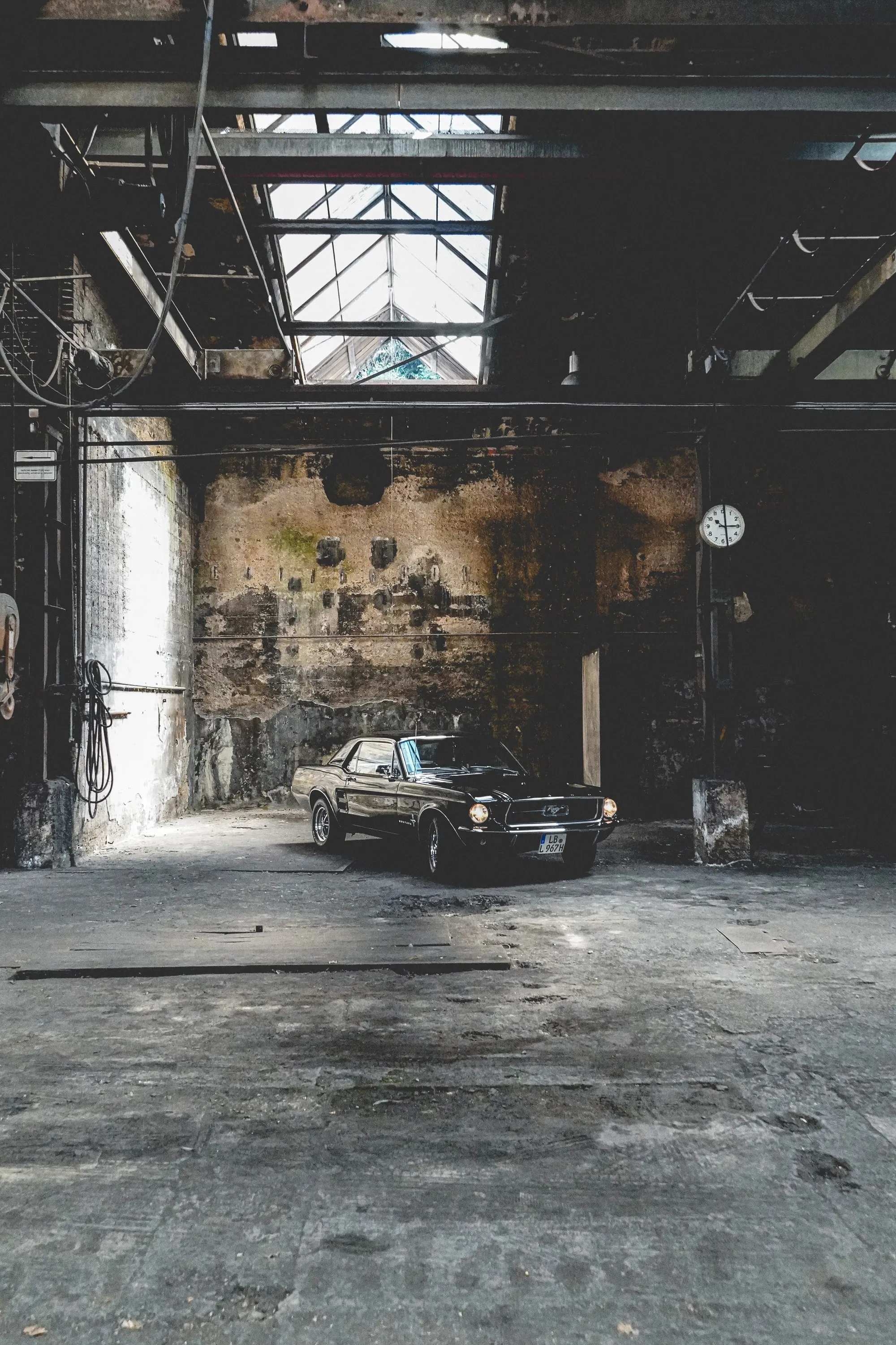 A car standing in an abandoned industrial hall, lit from tall side windows.