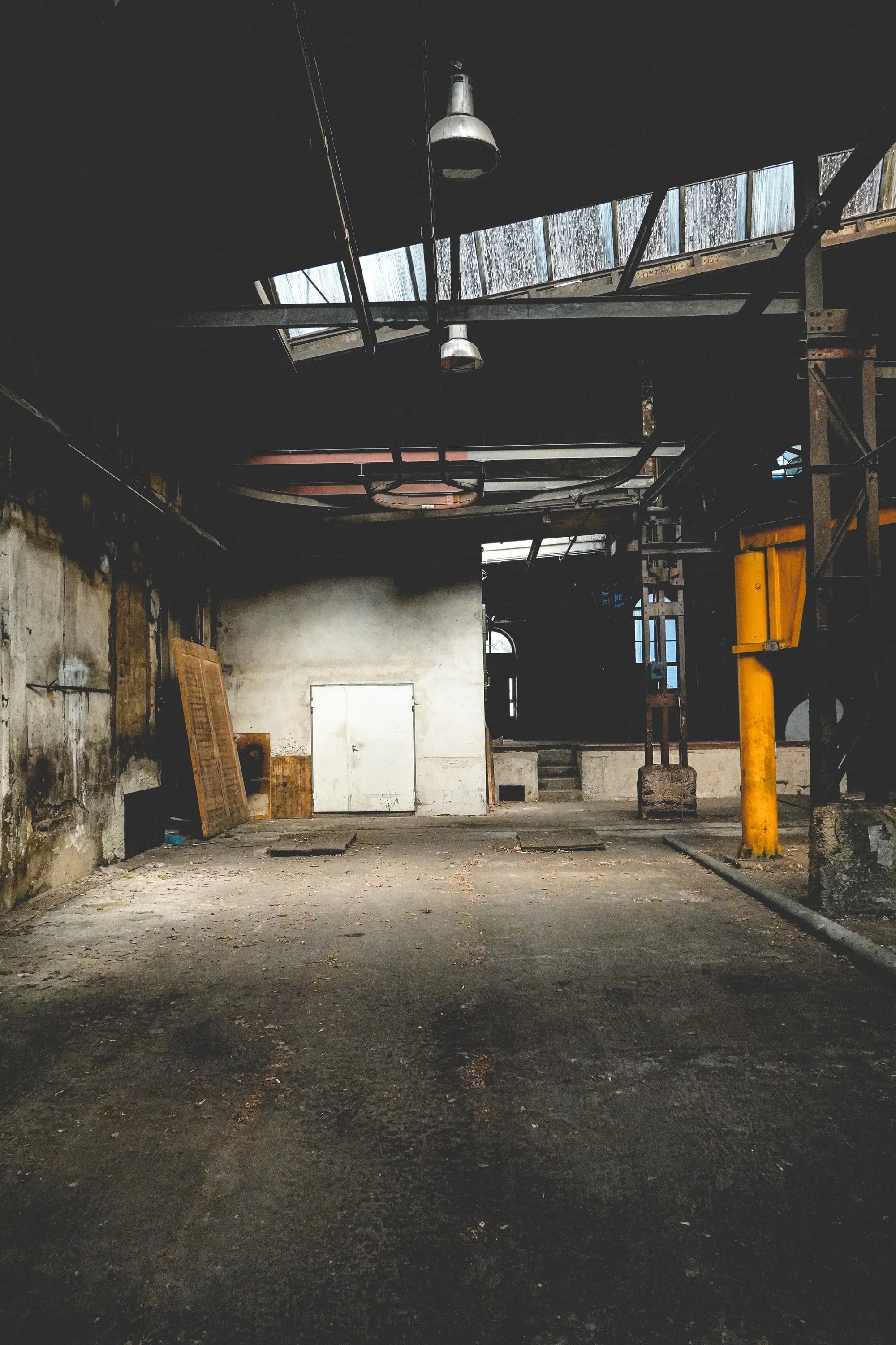 An empty loading bay beneath a run of dusty skylights.